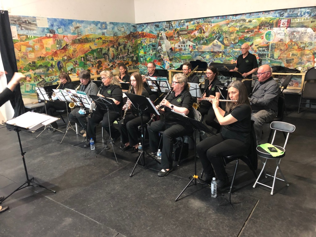 The Lumsden Community Band performs in front of a brightly coloured painting at the Lumsden Rink
